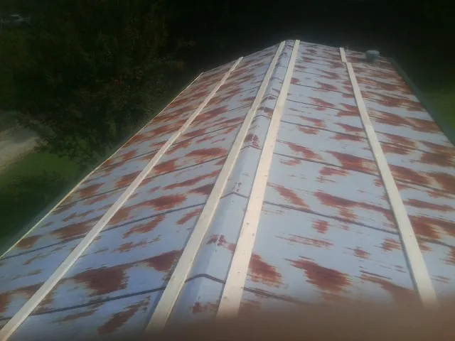 Rusted metal roof panels with new wood purlins before replacement — Storm Damage Roof Repair in Carlos by Roofing Brothers