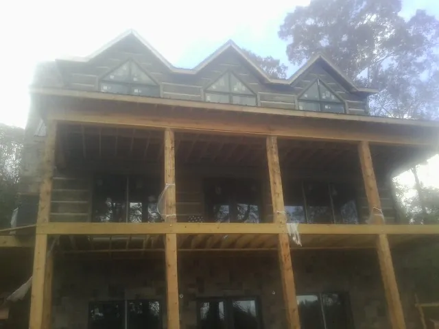 Dormers and porch framing on a large log home under construction — Roof Coating work by our crew in Carlos
