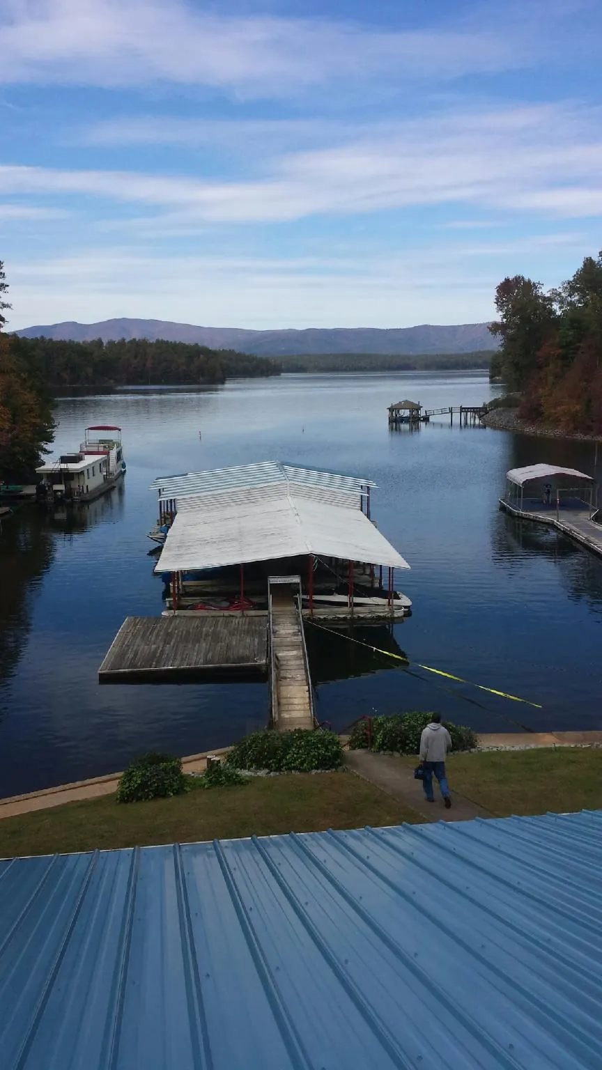 View across a lake from a newly installed blue metal roof in Carlos
